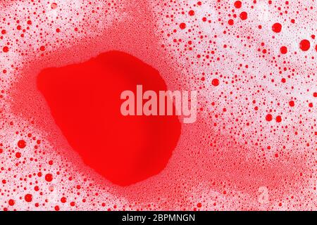 Foam with bubbles on red background. Shampoo or detergent in water. Flat lay. Stock Photo