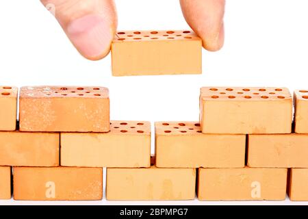 man is inserting a red brick in a wall Stock Photo