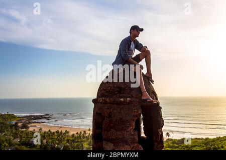 A traveller from Delhi enjoying the amazing natural view from Chapora Fort located in North Goa, Goa India. Vagator Beach is one of the most beautiful. Stock Photo