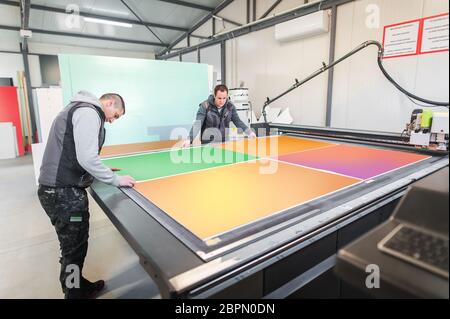Two printshop worker technicians works on large CNC computer numerical control printing and cutting machine Stock Photo