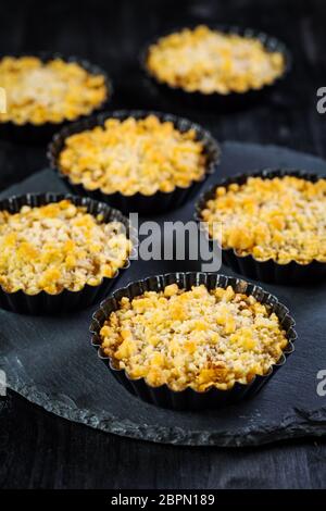 Small and delicious apple pies or apple crumble on black background. Apple tart. Stock Photo
