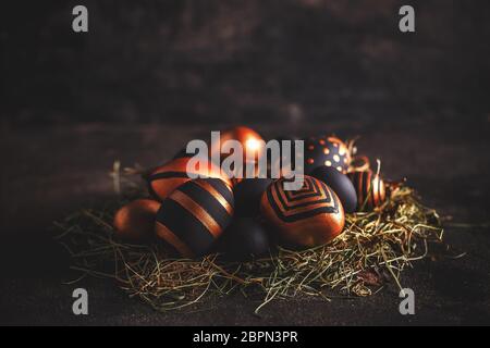Easter greeting card. Black and golden eggs with stripes and dots on black background Stock Photo