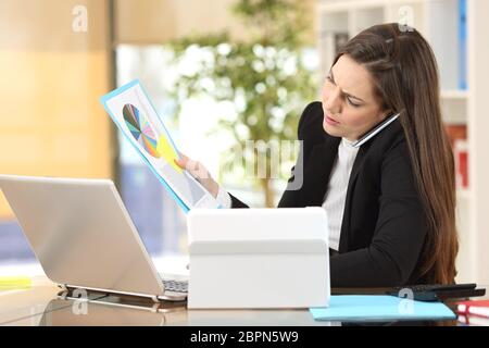 Angry businesswoman calling on the phone while is watching documents at office interior Stock Photo