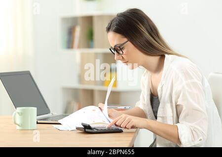 Side view portrait of a concentrated woman doing accounting at home Stock Photo