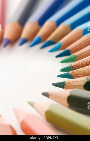 Close up semicircular crayons in blue and green tones on white background. Stock Photo