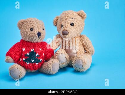 two teddy bears are sitting side by side on a blue background Stock Photo