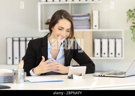 Office worker having a video call with a smart phone on a desktop Stock Photo