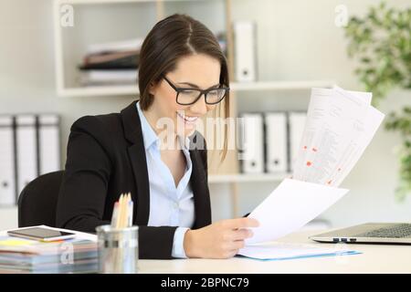 Happy office worker wearing eyeglasses comparing paper documents Stock Photo
