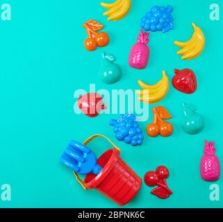 plastic childrens toys in the form of fruit and a bucket on a green background, copy space Stock Photo
