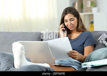 Desperate disabled self employed solving problems on phone sitting on a couch in the living room at home Stock Photo