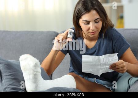 Disabled woman reading pills leaflet sitting on a couch in the living room at home Stock Photo
