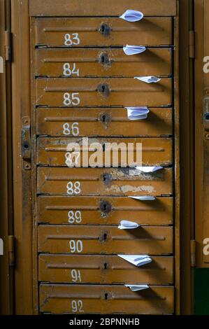 Old mailboxes in the entrance hall of a residential house filled with white paper flyers. Mass mailing concept Stock Photo