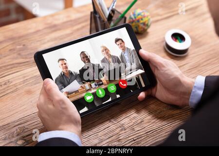 Elevated View Of A Businessman Videoconferencing With Her Colleagues On Digital Tablet Stock Photo