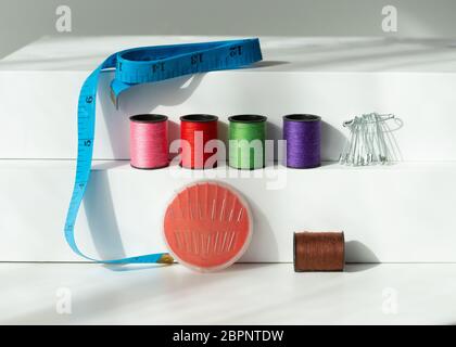 Creative composition with spools of colored threads and scissors. Sewing accessories, tailoring set. Stock Photo