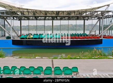 green pedal boats and red canoes stored on a open-air stage at the river embankment in winter, Tulln, Austria Stock Photo