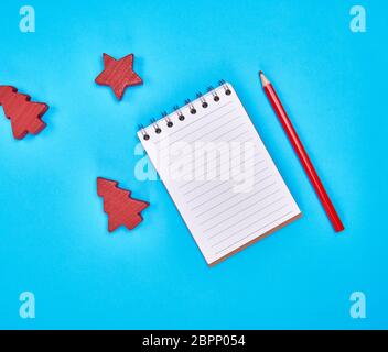 small notebook with empty white sheets in line and red wooden pencil, blue background, empty space Stock Photo