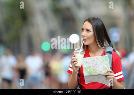 Teen tourist sightseeing drinking smoothie and holding a guide on the street Stock Photo