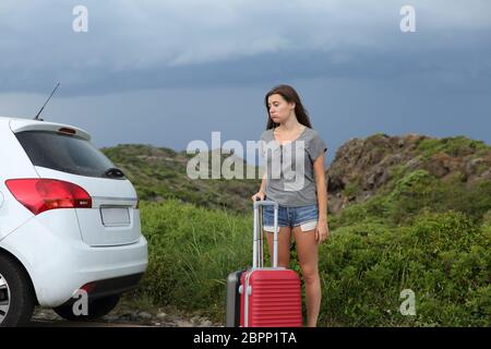 Frustrated car driver waiting for assistance after breakdown with a storm in the background Stock Photo