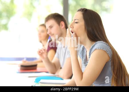 Side view of a bored student yawning during a class in a classroom Stock Photo