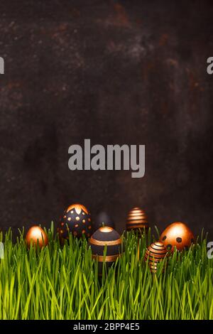 Easter composition with golden and black eggs hiding in green grass, copy space Stock Photo