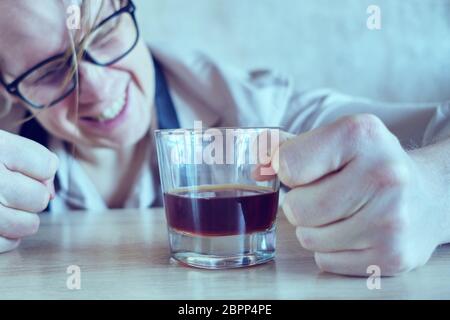 A drunk man in a shirt and tie is banging his fist on the table. Toned. Close up. Stock Photo