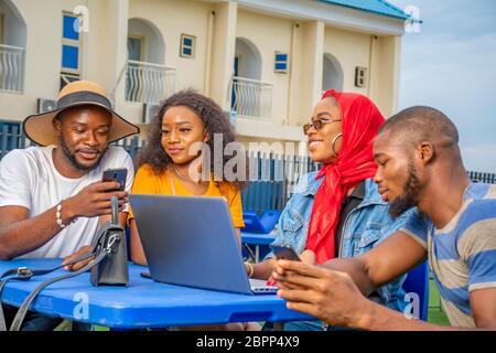 young black friends hanging out outdoors, using different media gadgets, lifestyle Stock Photo