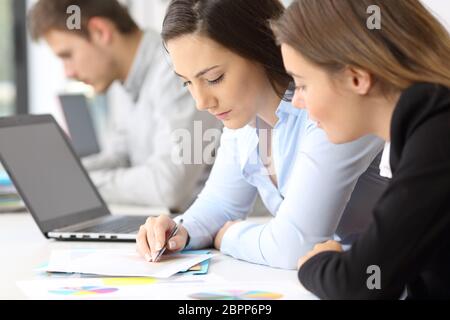 Close up of two concentrated employees coworking analyzing data in paper documents at office Stock Photo