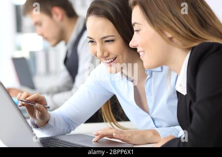 Two businesswomen working together on line with a laptop at office Stock Photo