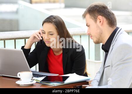 Two frustrated executives working sitting in a coffee shop outdoors Stock Photo