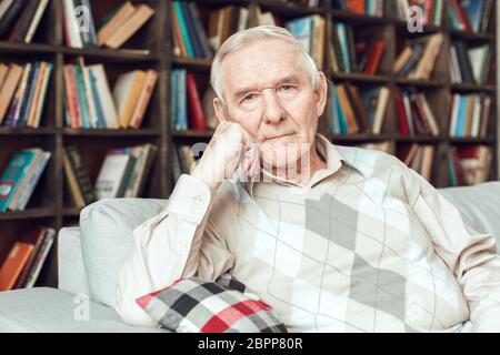 Senior man alone sitting at library thinking Stock Photo