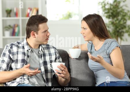 Angry couple arguing sitting on a couch at home Stock Photo