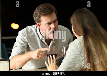 Angry couple arguing furiously in a bar at night Stock Photo