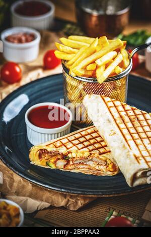 Pub snack. Tortilla wraps with grilled chicken fillet served with french fries and chili sauce Stock Photo