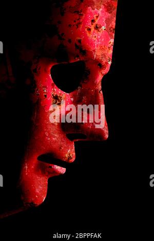Robot rusty decaying red face mask side view close up with textured skin and blank eyes. Black background and space for text. Artificial intelligence Stock Photo