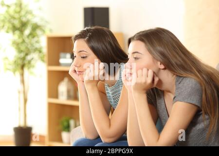 Bored roommates or friends sitting on a sofa in the living room at home Stock Photo