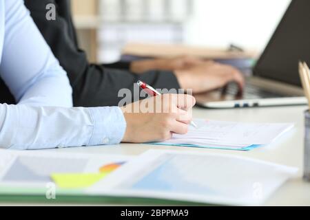 Close up of two office worker hands working managing documents and using a laptop online Stock Photo