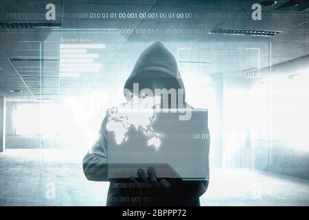 Hacker in black hoodie holding laptop on the room with virtual screen background Stock Photo