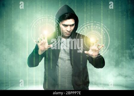 Young asian hacker in black hoodie touching virtual screen with binary code over green background Stock Photo