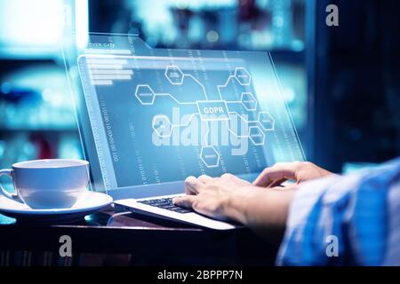 Businessman working using laptop with virtual screen display the GDPR protection structure and binary with coffee on the table at office room backgrou Stock Photo