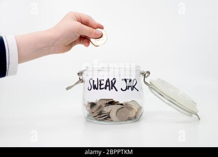 Childs hand putting coin into swear jar Stock Photo