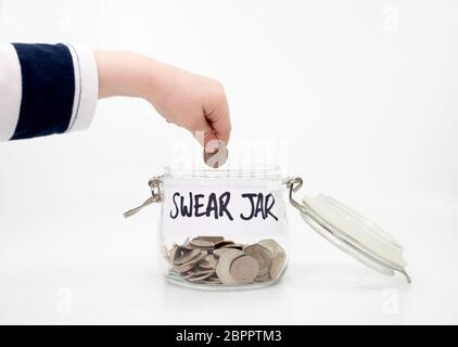 Childs hand putting a coin into a swear jar Stock Photo