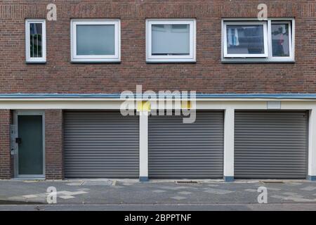 View of shutter doors of garages under typical design of housing or apartment in Europe with rectangular windows and vintage brick facade. Stock Photo