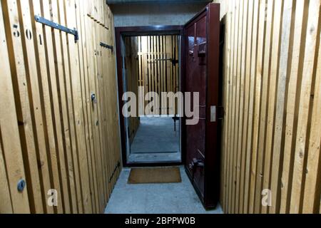 Inside of a bunker with a wooden interior and an open metal door to protect from a bomb attack Stock Photo