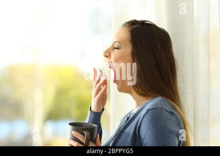 Side view portrait of a woman yawning in the morning at home Stock Photo