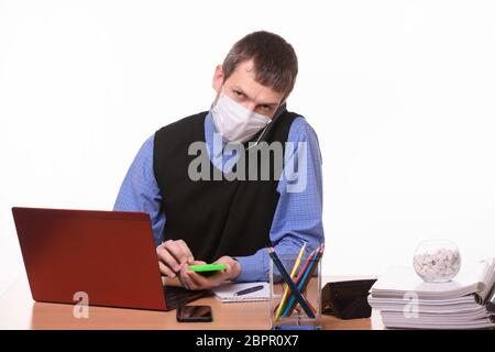 An office worker in a protective medical mask is talking on the phone, counting on a calculator and looking at the frame Stock Photo