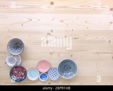 different kinds of modern colourful crockery on light wood background Stock Photo