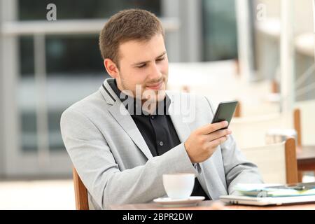 Serious executive using a mobile phone sitting in a coffee shop Stock Photo