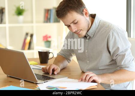 Freelance worker working on line at home reading documents on a desk Stock Photo