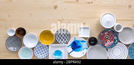 different kinds of modern colourful and white crockery on light wood background Stock Photo