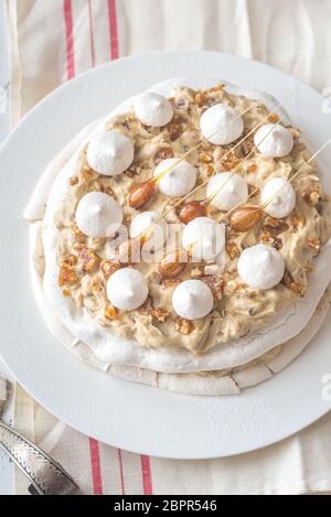 Pavlova cake with caramel and almonds on the wooden background Stock Photo